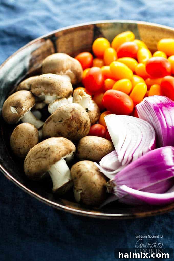 Succulent Grilled Chicken Skewers 3 A close up photo of mushrooms, chopped red onion and tomatoes in a bowl.