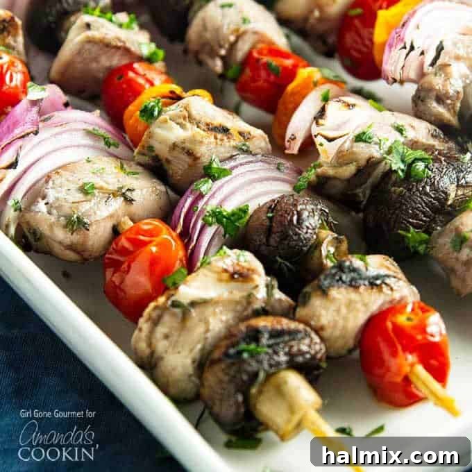 Succulent Grilled Chicken Skewers 4 A close up of marinated chicken skewers with tomatoes, red onions and mushrooms.