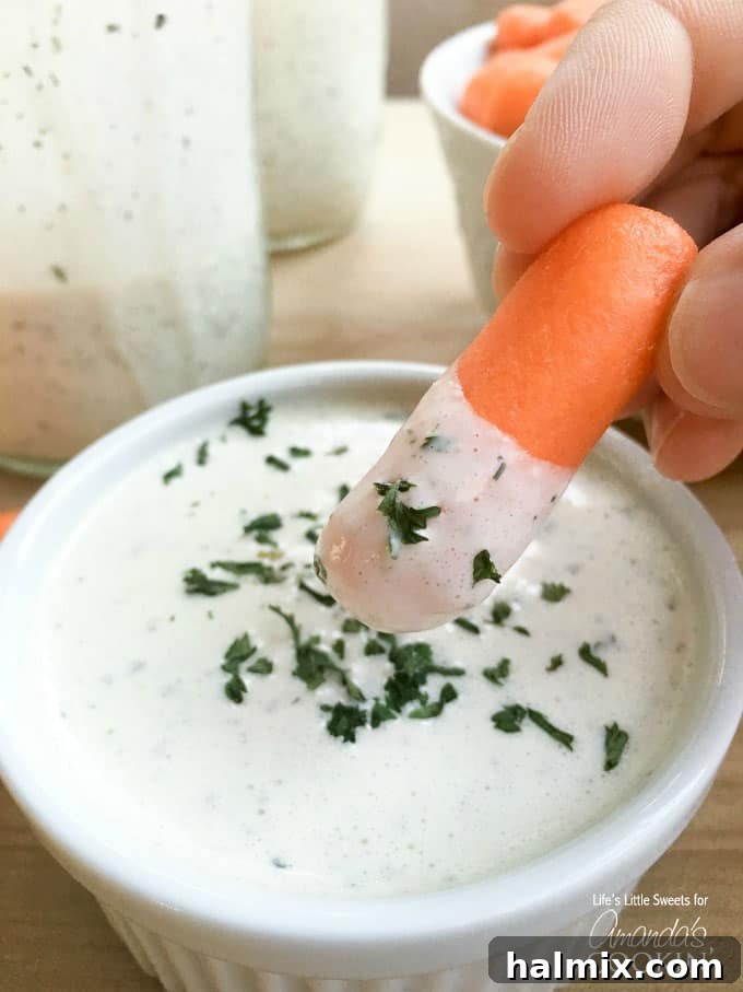 Try this delicious buttermilk ranch dressing recipe at home instead of buying another bottle. This homemade ranch dressing is creamy, delicious and fresh! Close-up of a hand dipping a fresh carrot stick into a bowl of creamy homemade buttermilk ranch dressing