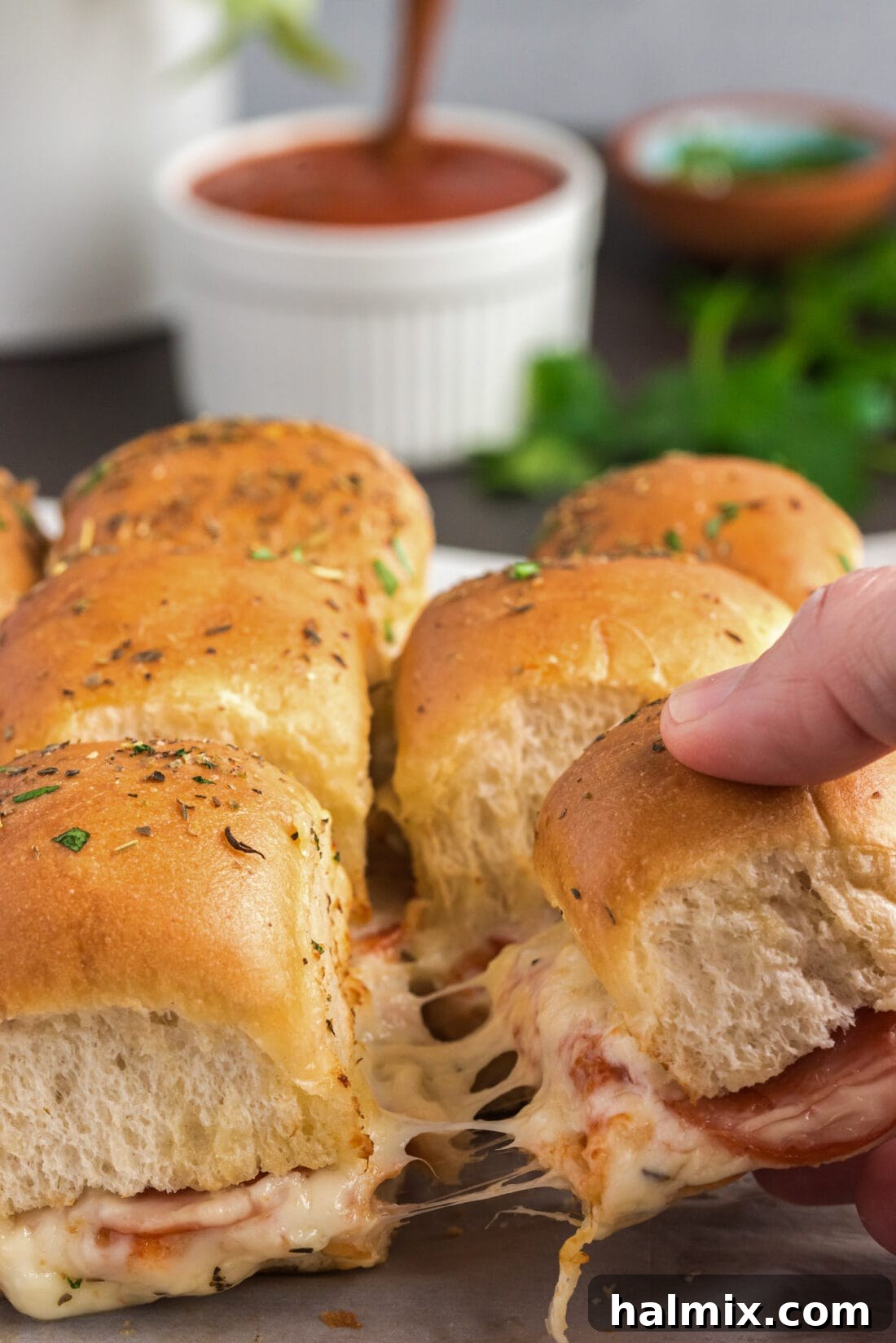 Cheesy Pizza Buns 3 Hand pulling away a Pizza Slider from the rest