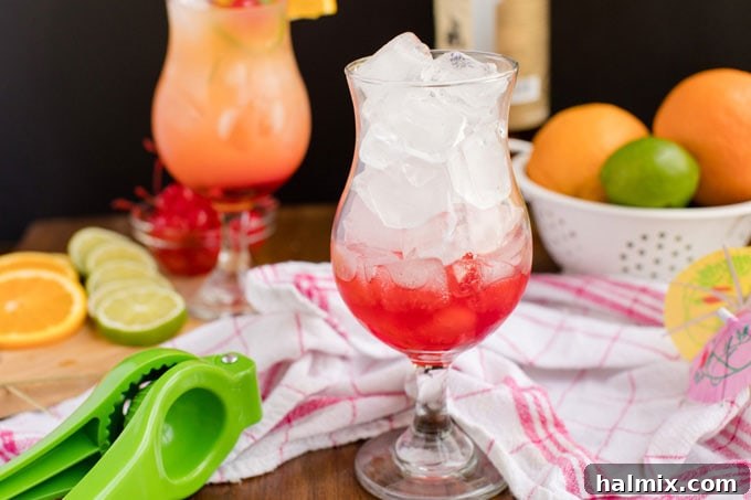 Island Elixir 8 A hurricane glass filled to the brim with ice cubes, showcasing the vibrant red layer of grenadine settled at the bottom, ready for the rum punch.