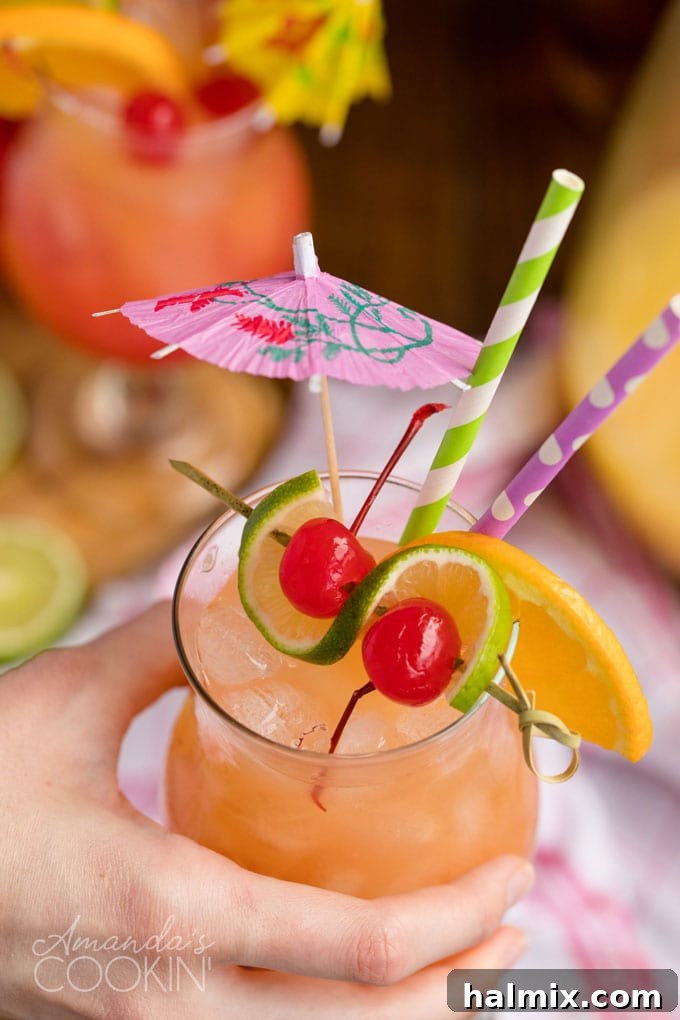 Island Elixir 10 A hand holding a perfectly garnished glass of vibrant rum punch, ready to be enjoyed, showcasing the refreshing colors and tropical appeal.