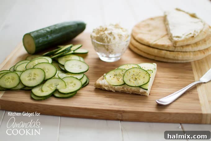 Simple Ingredients, Extraordinary Flavor Ingredients for cucumber sandwiches: sliced cucumbers, pita bread, and a bowl of seasoned cream cheese spread on a wooden cutting board.