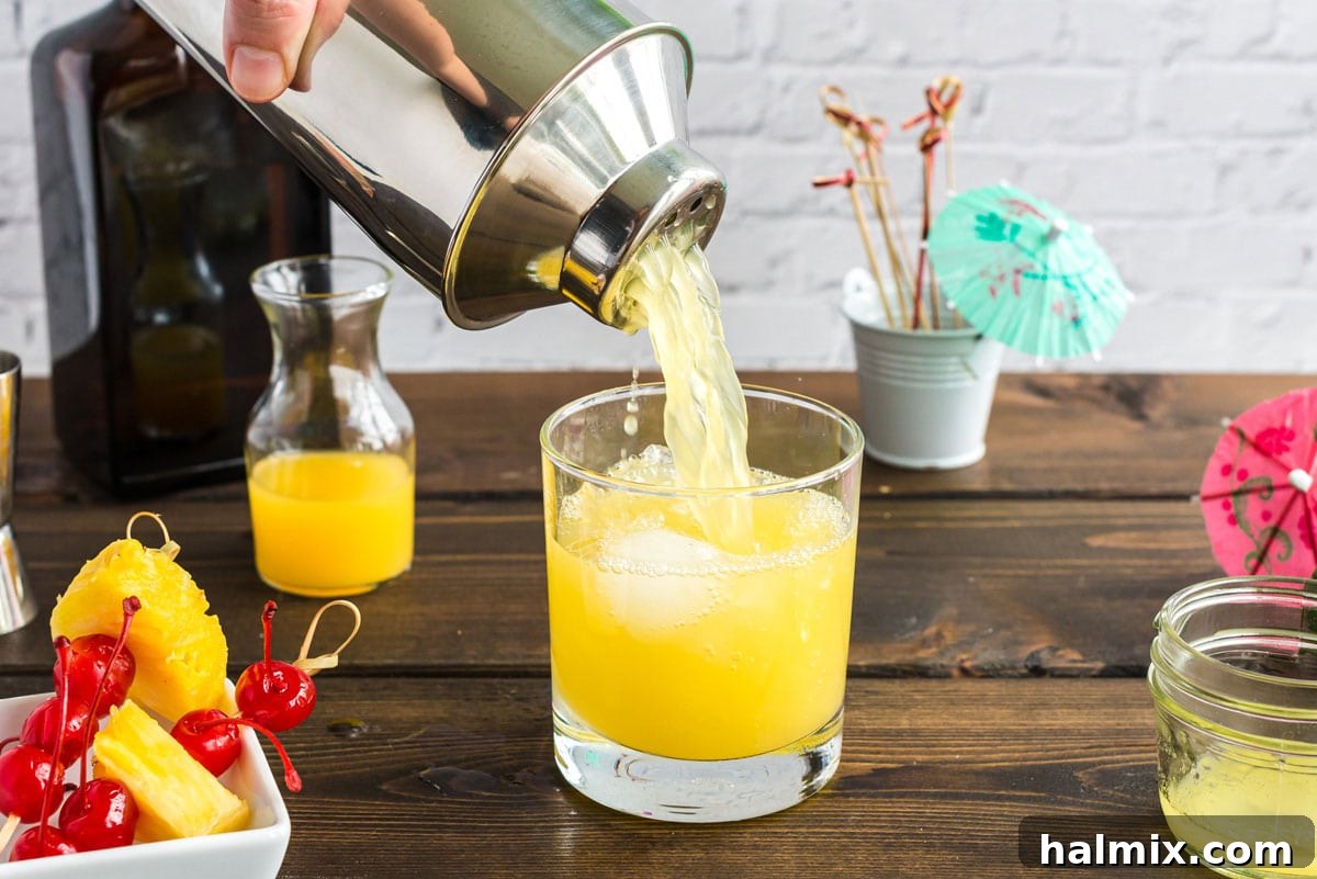 pouring mai tai out of cocktail shaker and into a glass