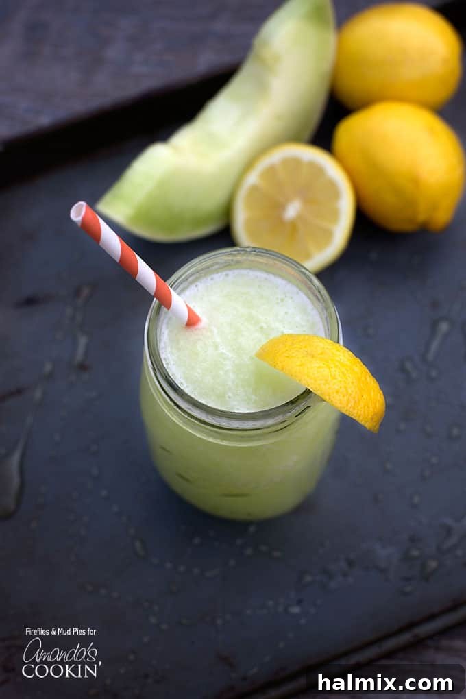 A vibrant honeydew lemon slush in a mason jar, garnished with a fresh lemon wedge and served with a striped straw on a light background.