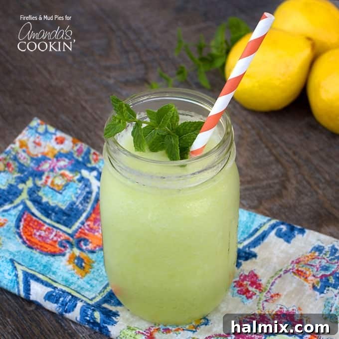 A close-up of a mason jar filled with bright green honeydew lemon slush, topped with a fresh mint sprig and a red and white striped straw, against a soft focus background.