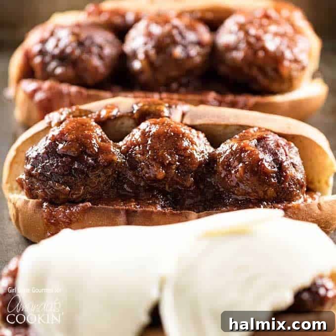Saucy Slow Cooker BBQ Meatball Heroes 2 A close up photo of three slow cooker BBQ meatball subs, one topped with provolone cheese, showing the melted cheese and toasted bun.