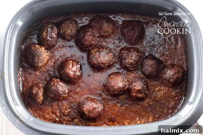 Saucy Slow Cooker BBQ Meatball Heroes 4 An overhead photo of meatballs simmering in a rich BBQ sauce in a slow cooker, showing the even coating of sauce.