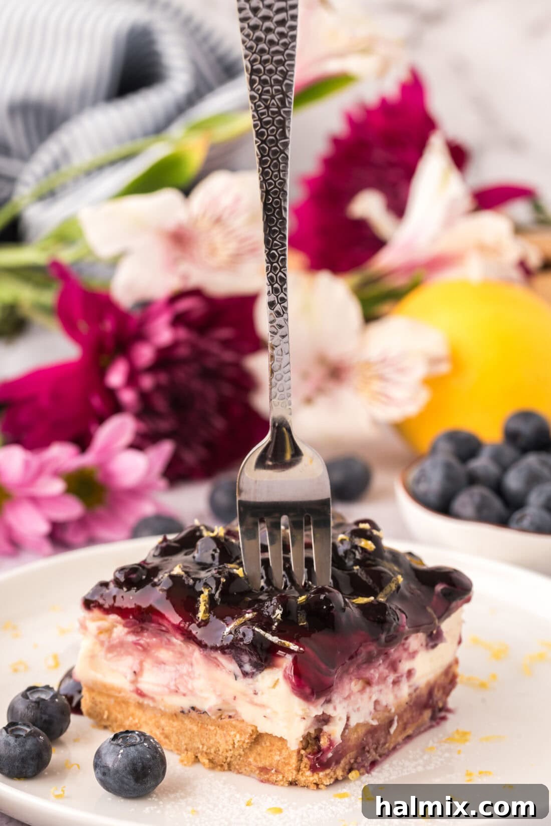 Fork pressing into a slice of No Bake Blueberry Cheesecake, showing the creamy texture