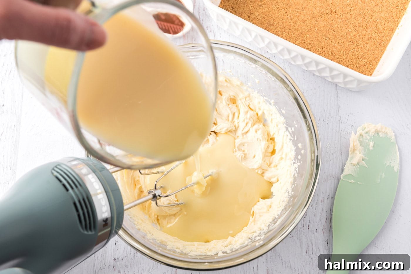 pouring sweetened condensed milk into mascarpone cheese mixture with a mixer