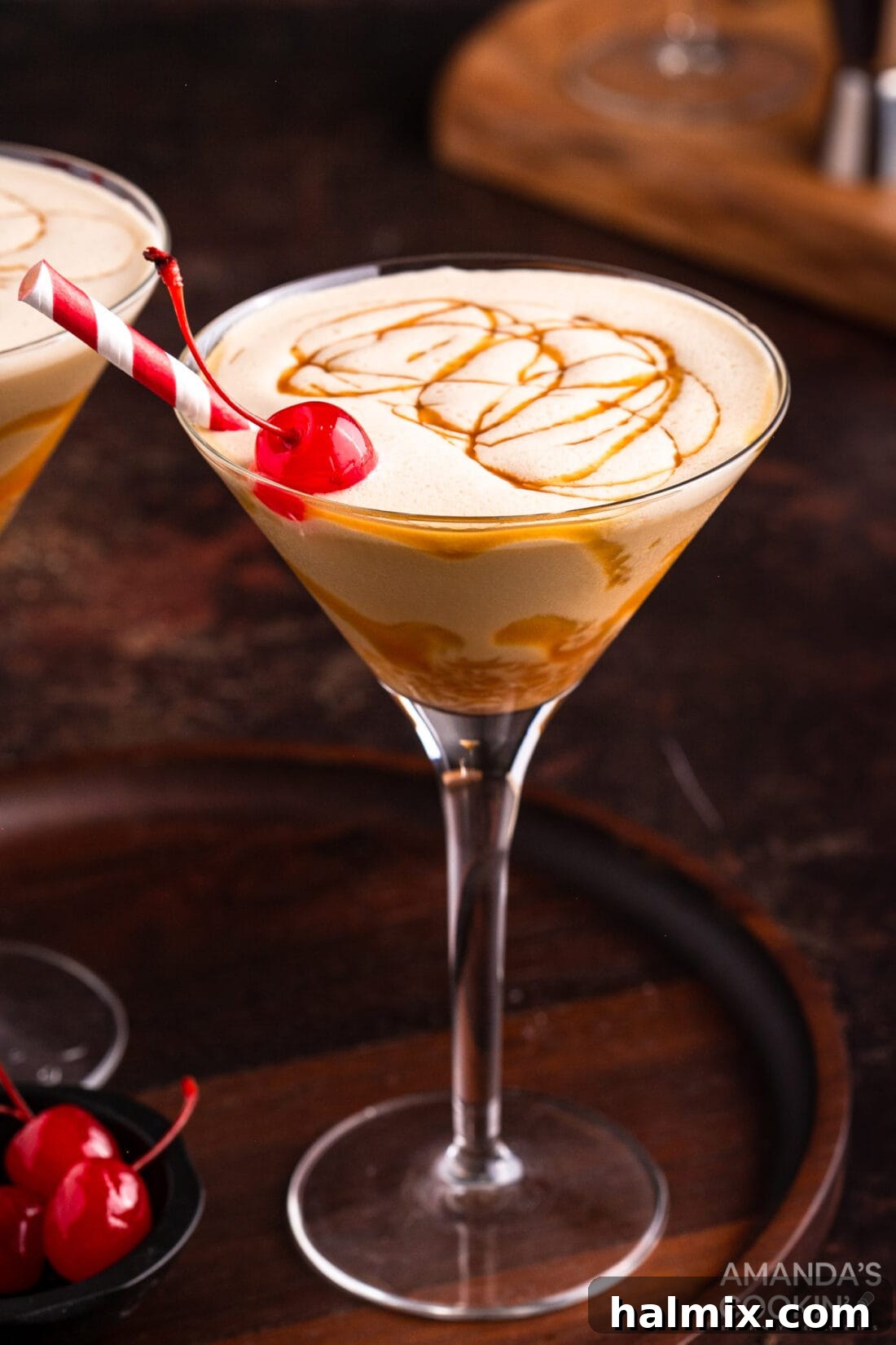 Spiked Butterscotch Shake 2 A martini glass filled with a creamy butterscotch milkshake cocktail, garnished with a vibrant red maraschino cherry.