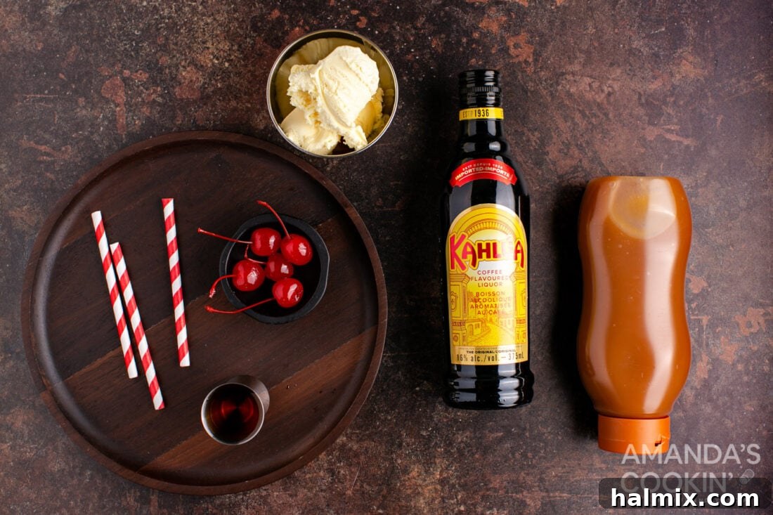 Spiked Butterscotch Shake 4 All the essential ingredients neatly arranged on a counter to prepare a butterscotch milkshake cocktail: butterscotch schnapps, Kahlua, vanilla ice cream, butterscotch topping, and maraschino cherries.