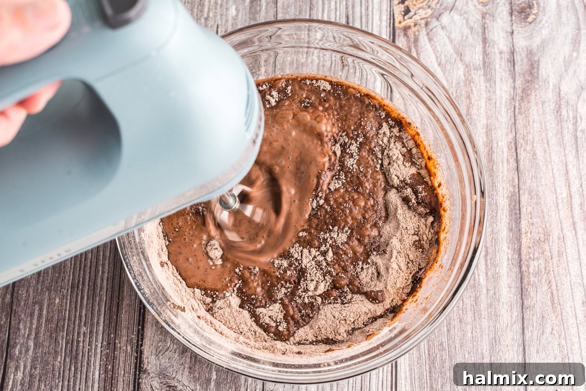 Bowl of pudding mix and milk being beaten with a hand mixer