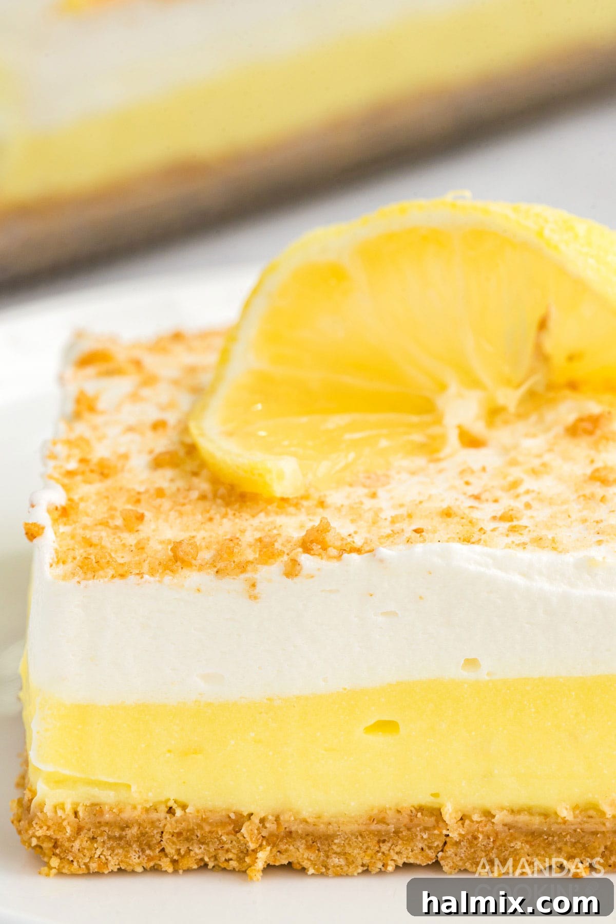 Close-up view of a vibrant, layered lemon cream cheese pudding dessert, showcasing its creamy texture and graham cracker crust.