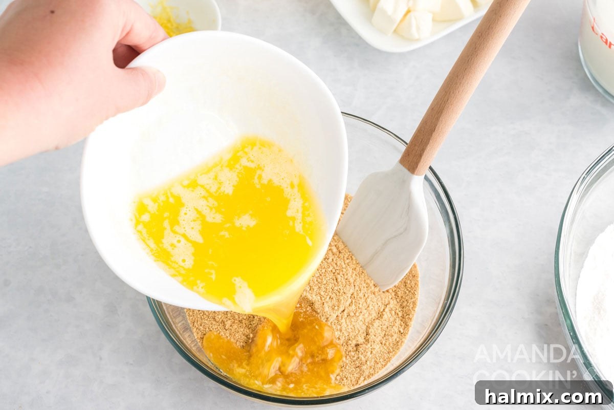 Pouring melted butter into a bowl of graham cracker crumbs for the crust.