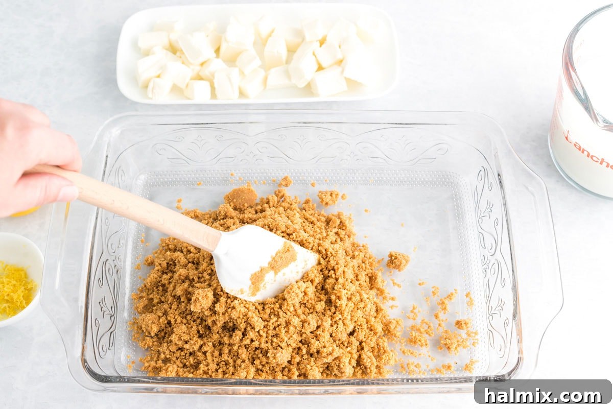 Firmly pressing graham cracker crumbs into a 13x9 inch baking pan to form the crust.