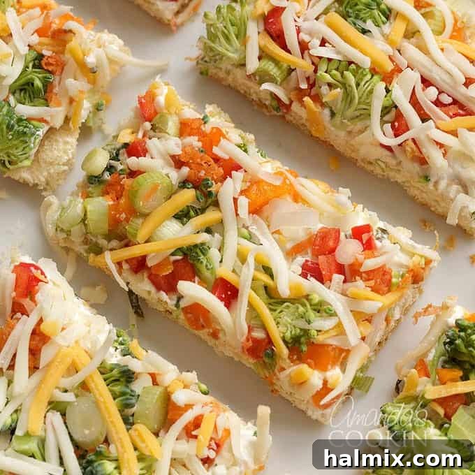 fresh veggies and cheese on cream cheese and crescent dough, representing a savory veggie pizza.