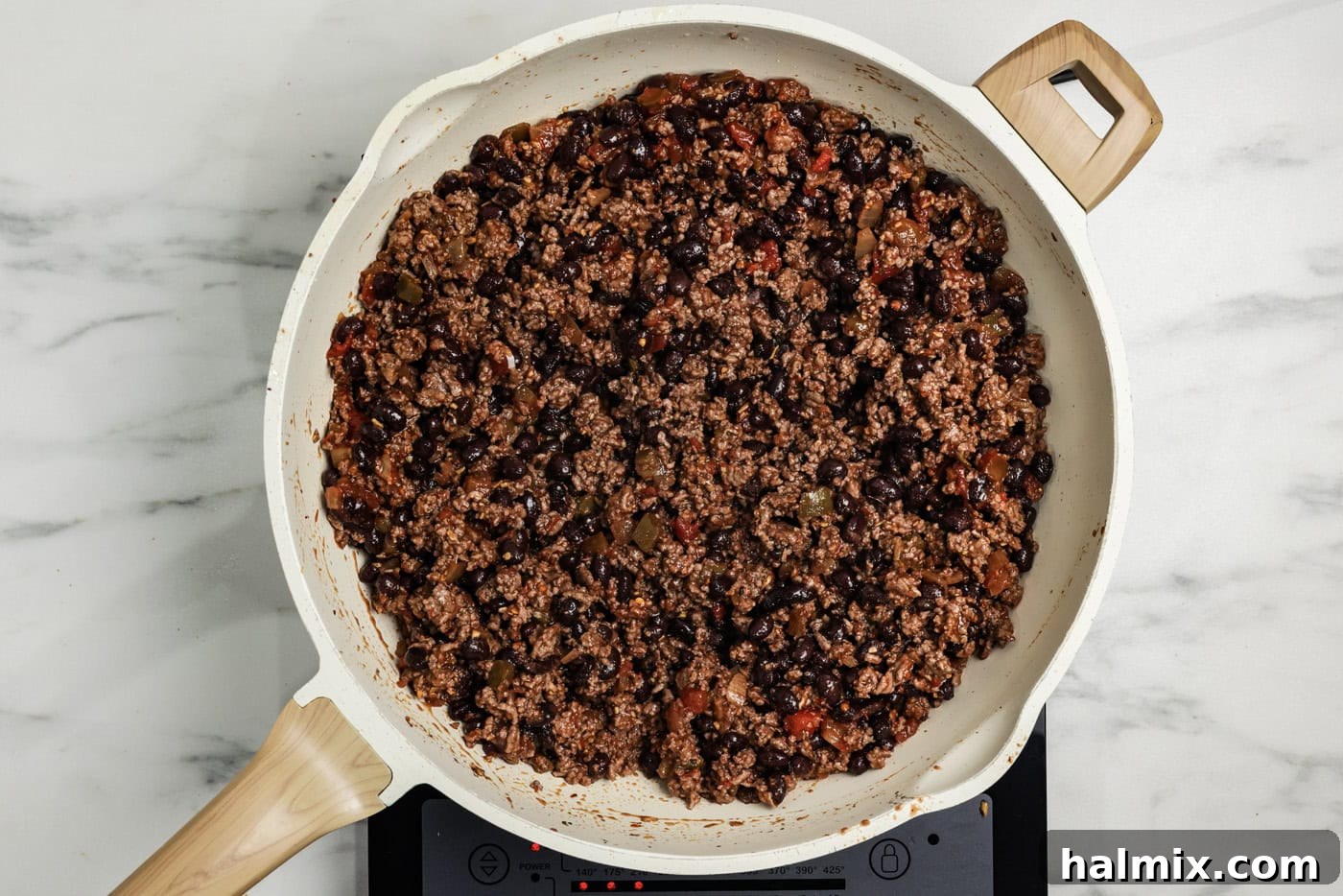 Ultimate Taco Bake 5 Cooked ground beef with black beans, seasoning, and salsa mixed together in a skillet