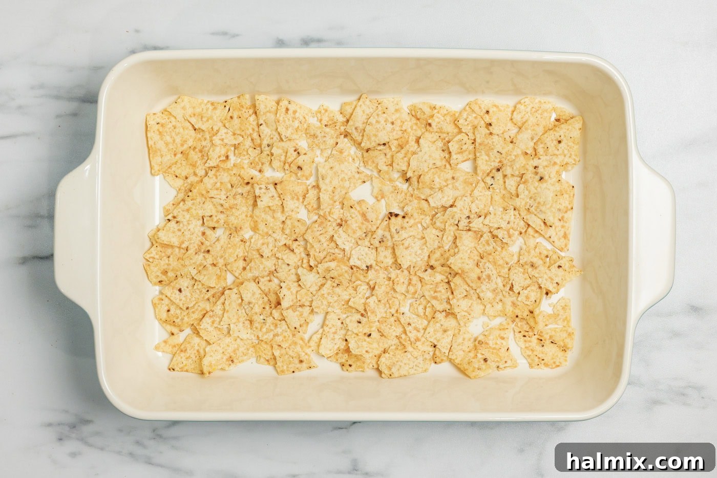 Ultimate Taco Bake 6 Slightly crumbled tortilla chips on bottom of a baking dish