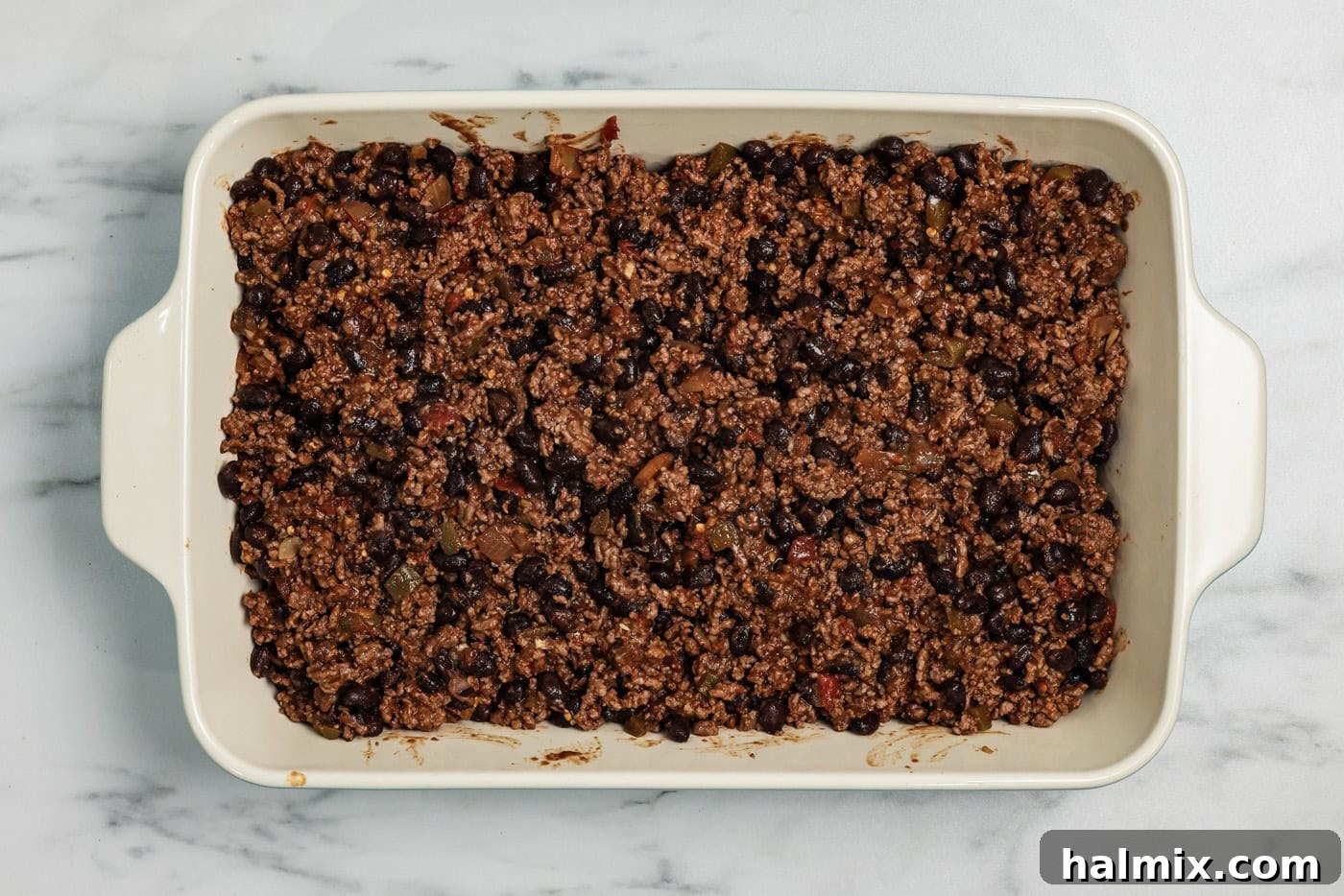 Ultimate Taco Bake 7 Ground beef mixture with beans added to a casserole dish