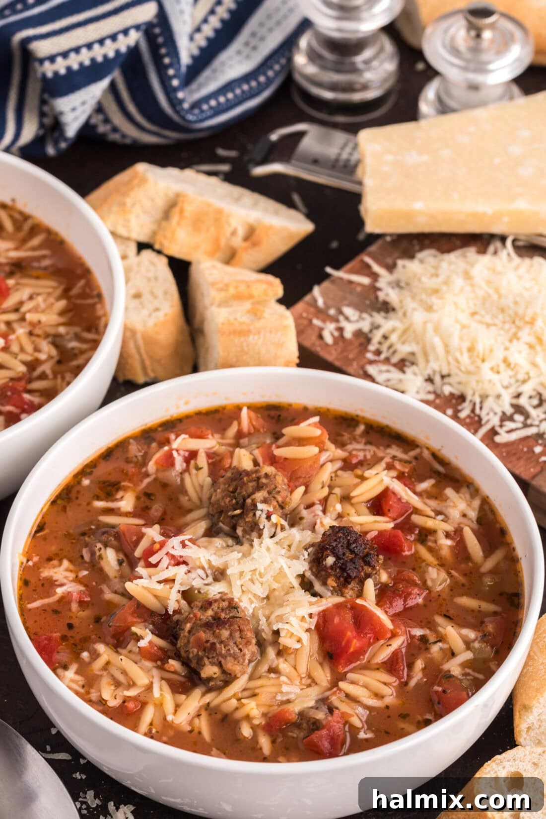 Savory Sausage Orzo Medley 2 Two bowls of Italian Sausage Tomato Orzo Soup with bread and cheese in the background