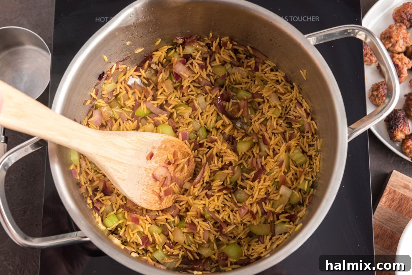 Savory Sausage Orzo Medley 7 wooden spoon in a pot with orzo, sausage, and veggies