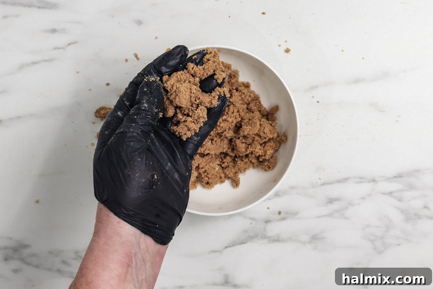 Gloved hand holding cinnamon streusel mixture