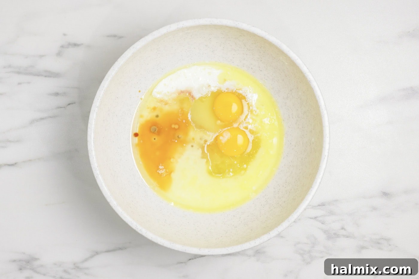 Sugar, eggs, milk, and vanilla in a mixing bowl