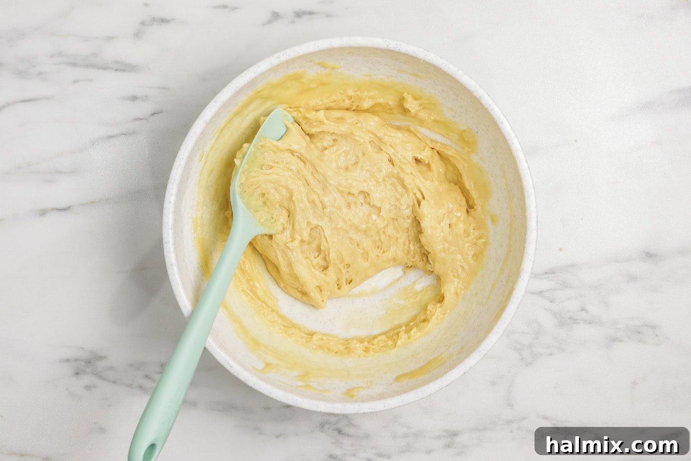 Rubber spatula in a bowl with vanilla muffin batter