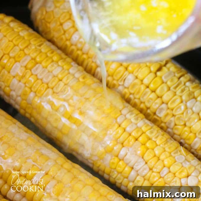 An overhead of melted butter being poured over corn.