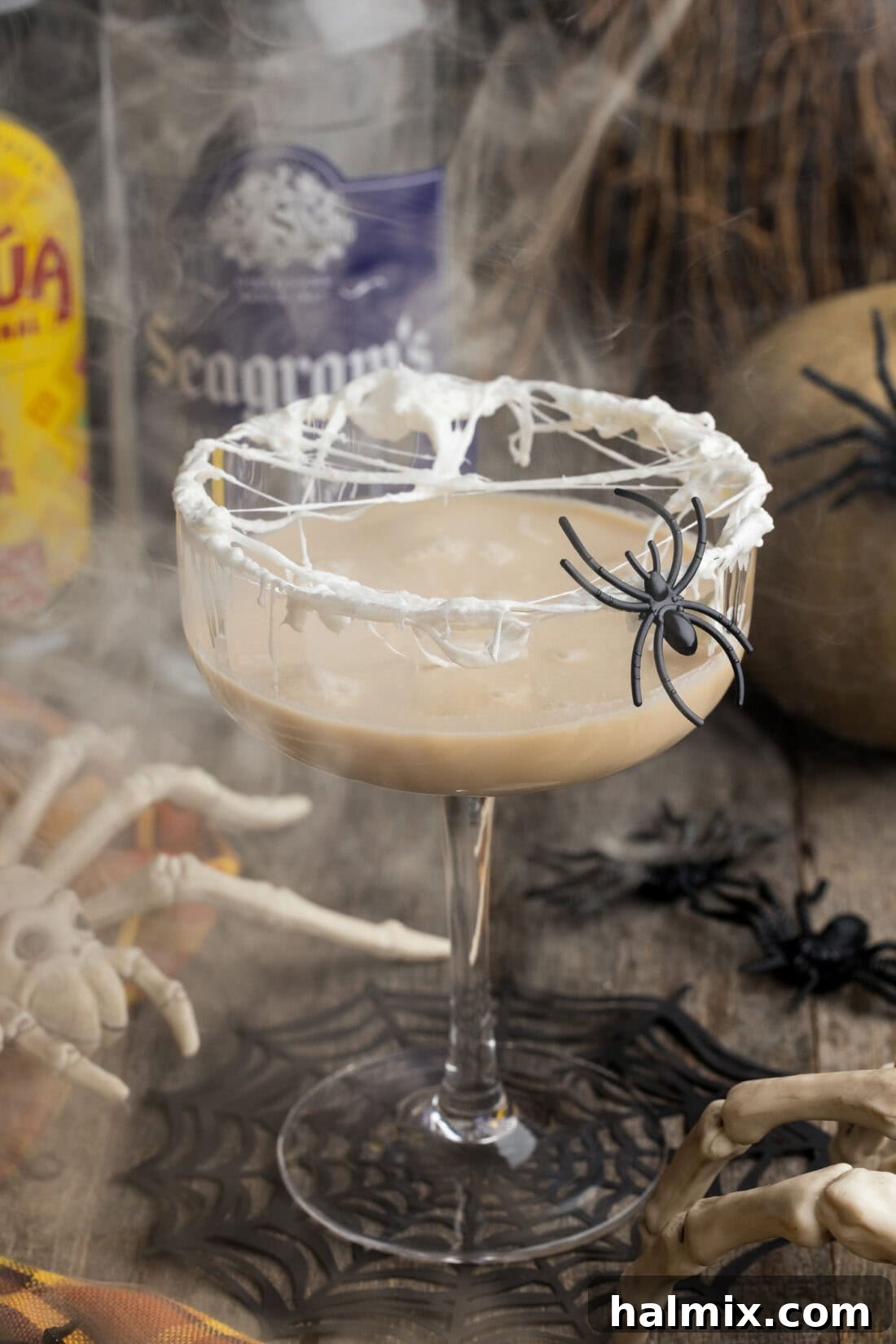 Spiderweb Cocktail casting a spooky silhouette with smoke in the background, highlighting the eerie ambiance.