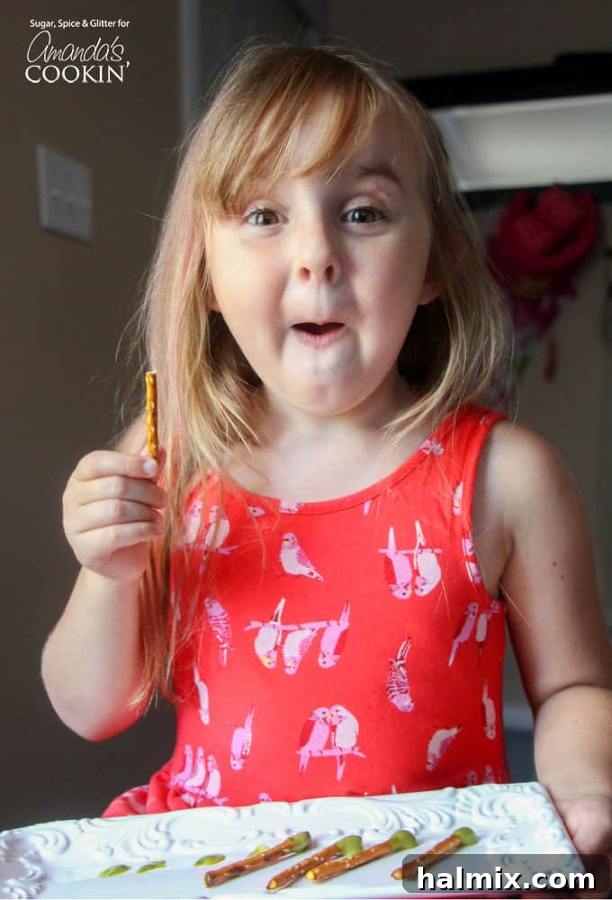 A little girl holding a pretzel stick, showcasing her delight and the simple appeal of this gross-out Halloween treat.
