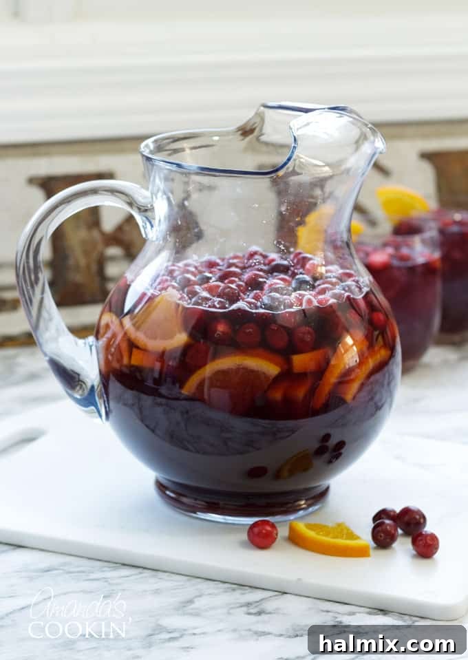 cranberry sangria in pitcher with cranberries and orange slices