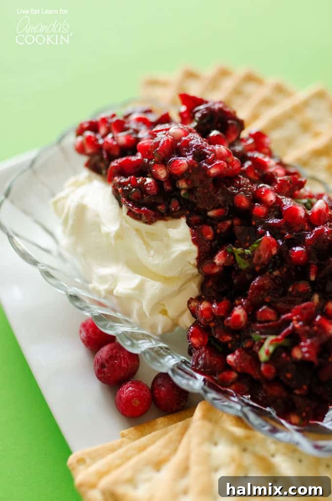 Festive Cranberry Salsa 2 A close up of cranberry salsa spooned over cream cheese in a glass dish.
