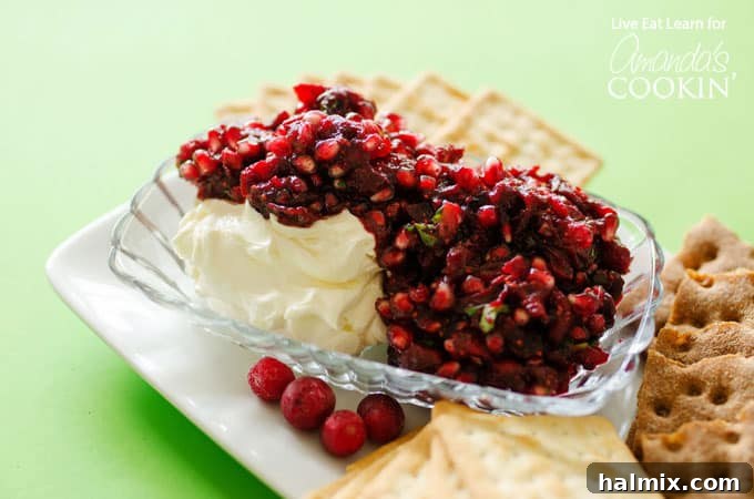 Festive Cranberry Salsa 4 Cranberry salsa spooned over cream cheese in a glass dish with cracker squares surrounding.
