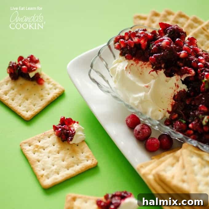 Festive Cranberry Salsa 5 Cranberry salsa spooned over cream cheese in a glass dish with cracker squares surrounding.