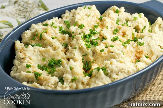A bowl of golden brown butter mashed potatoes with a sprinkle of fresh green chives on top.