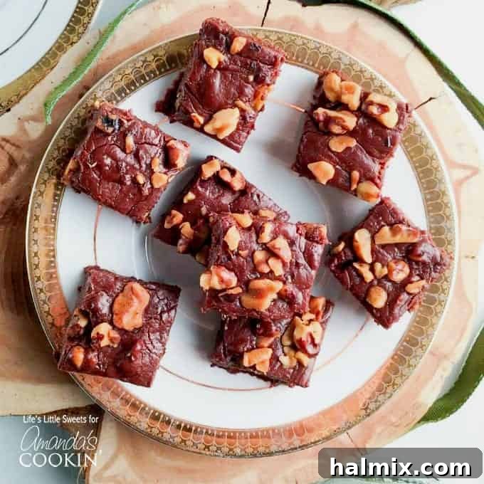 Chocolate walnut fudge squares arranged on a white and gold decorative plate.