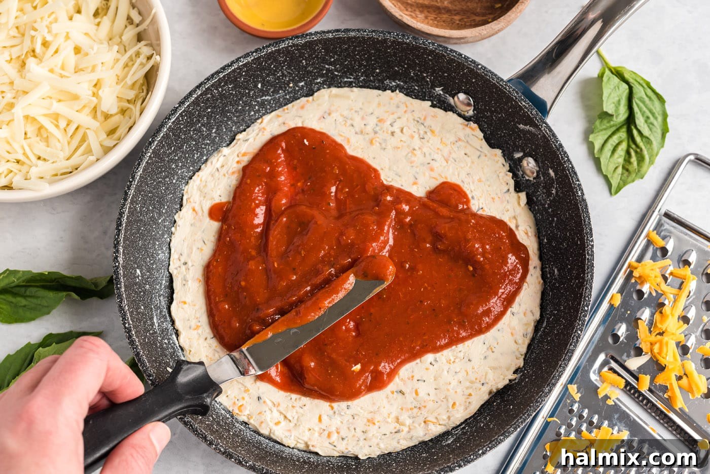 spreading pizza sauce over cream cheese mixture