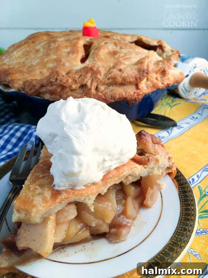 A slice of homemade apple pie on a plate with the whole pie in the background, showcasing its flaky crust and rich filling.