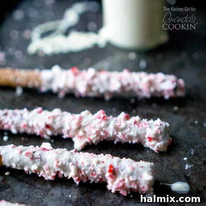 A close up photo of three white chocolate candy cane pretzel sticks.