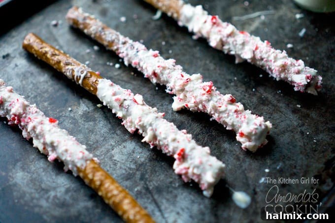 A close up photo of four white chocolate candy cane pretzel sticks.