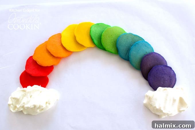Cooked rainbow pancakes stacked into a colorful arch, ready to be served for a fun breakfast.