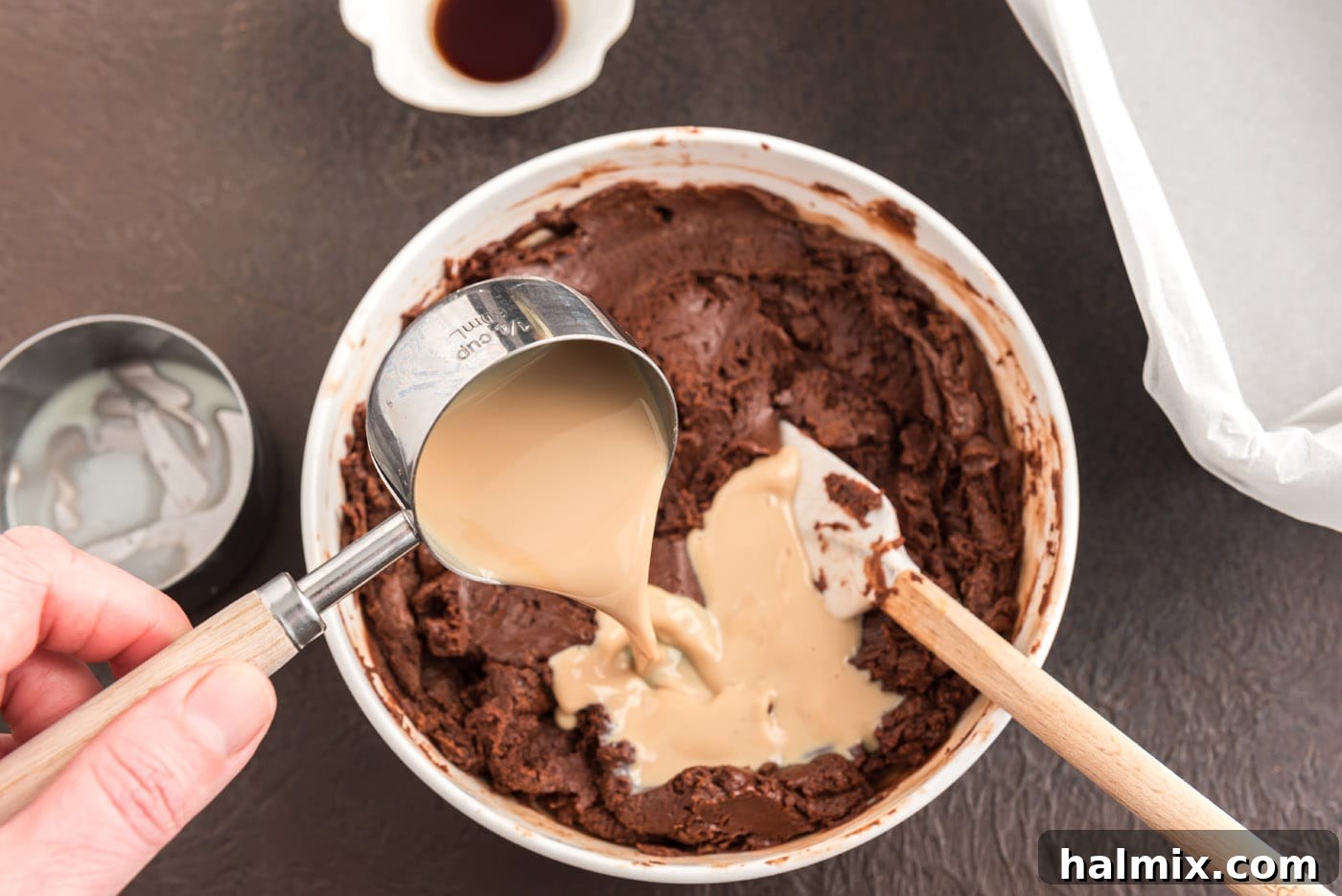 Baileys Irish cream being poured into the melted chocolate and condensed milk mixture.