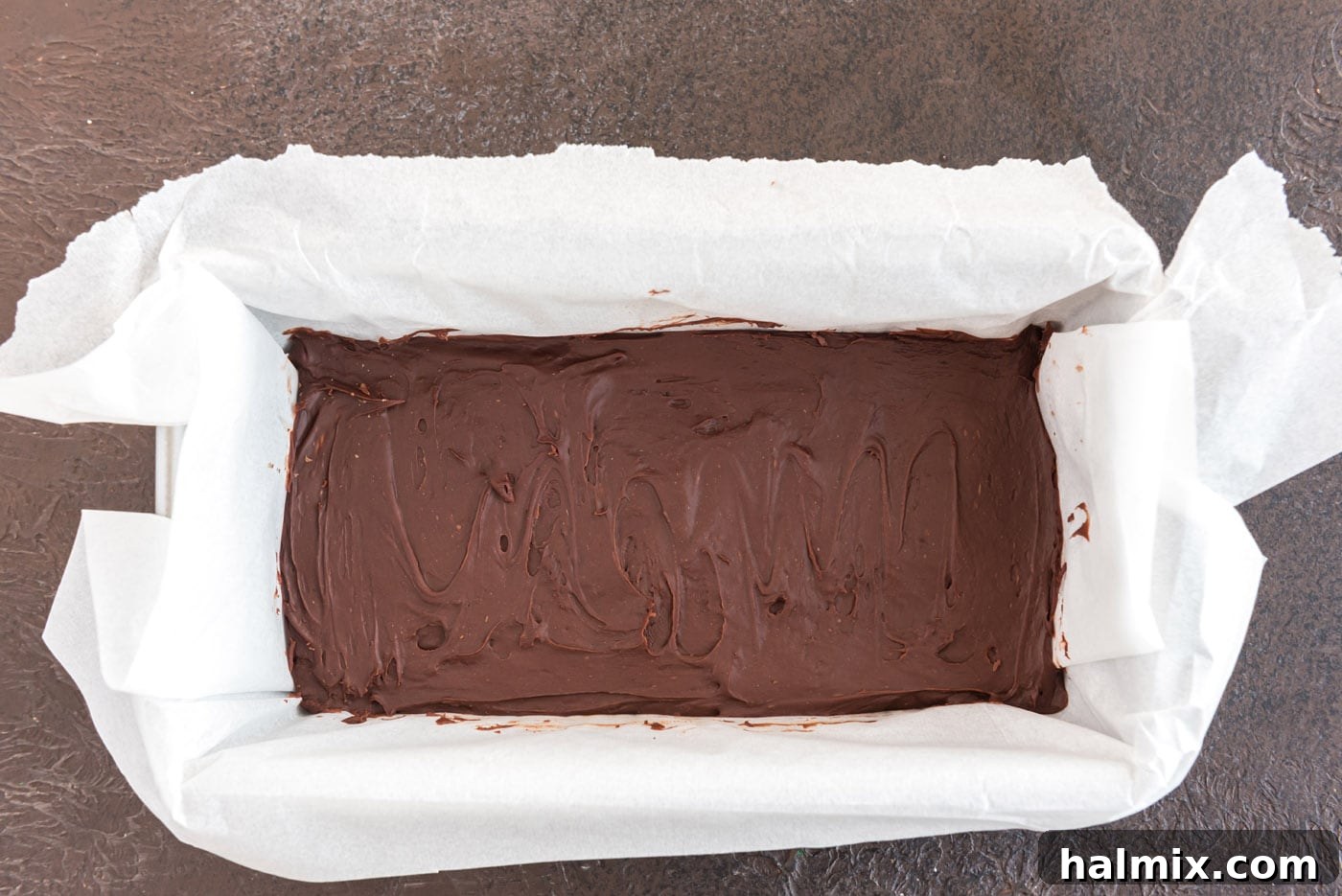 The no-cook chocolate fudge mixture chilling in a loaf pan in the refrigerator.