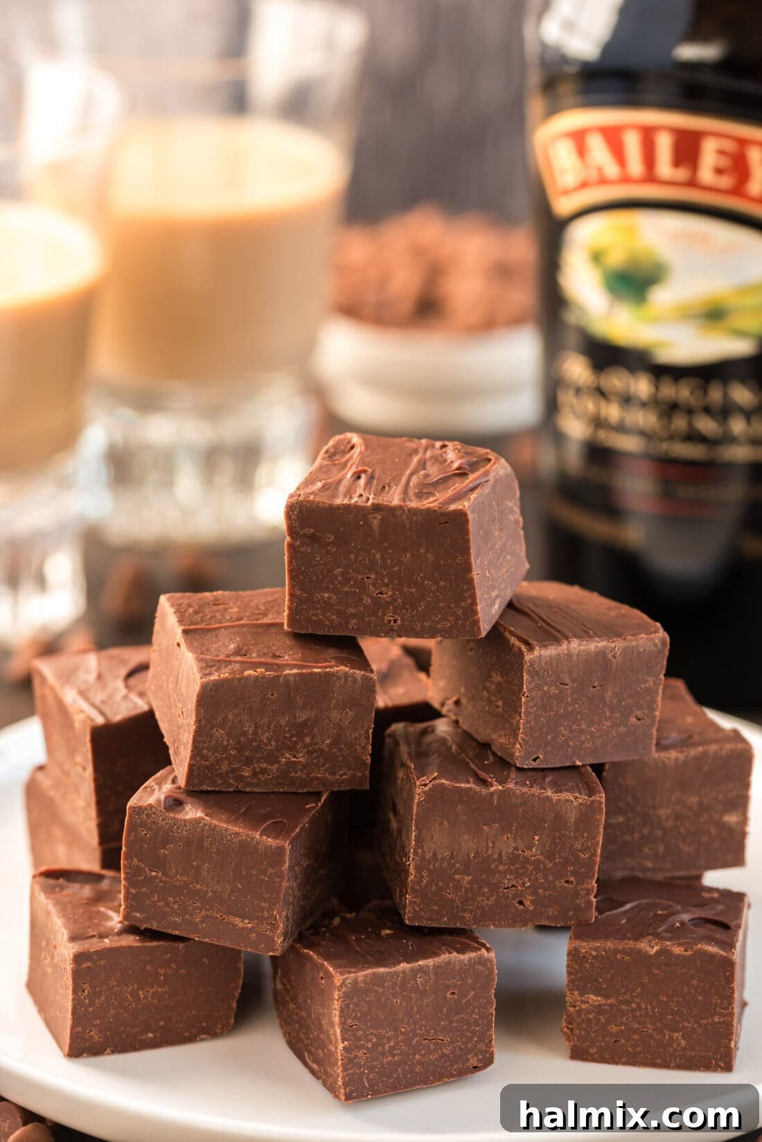 A close-up photograph of multiple 4-Ingredient Baileys Fudge squares stacked neatly, highlighting their rich texture.