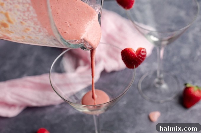 Pouring the blended strawberry mixture into the martini glass, forming the first beautiful layer of the Pink Mudslide.