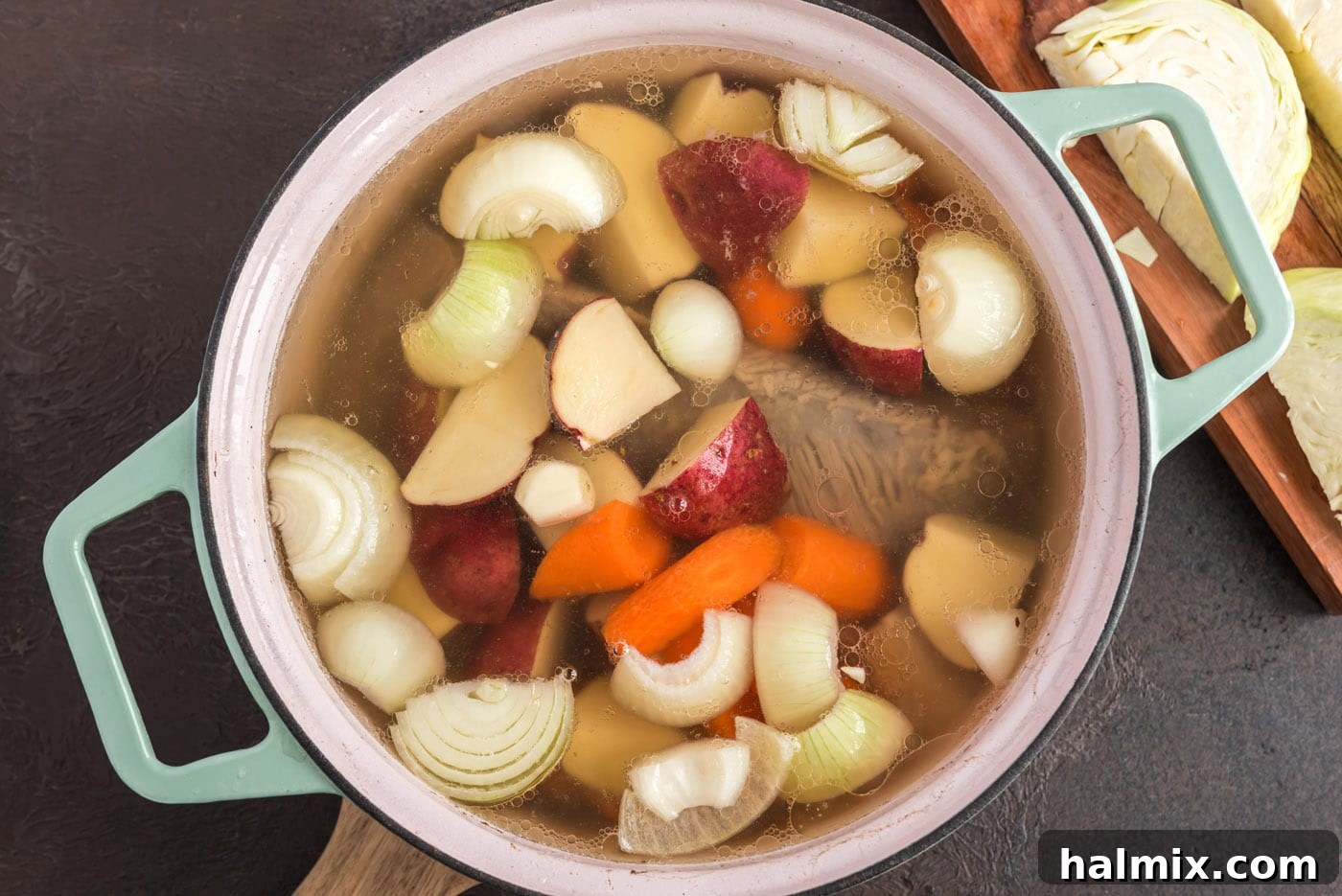 corned beef in Dutch oven with potatoes, onion, and carrots