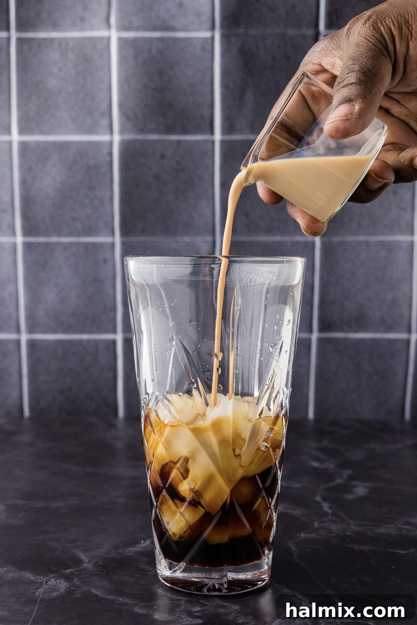 Hand pouring vodka into a cocktail shaker with Baileys and chocolate liqueur
