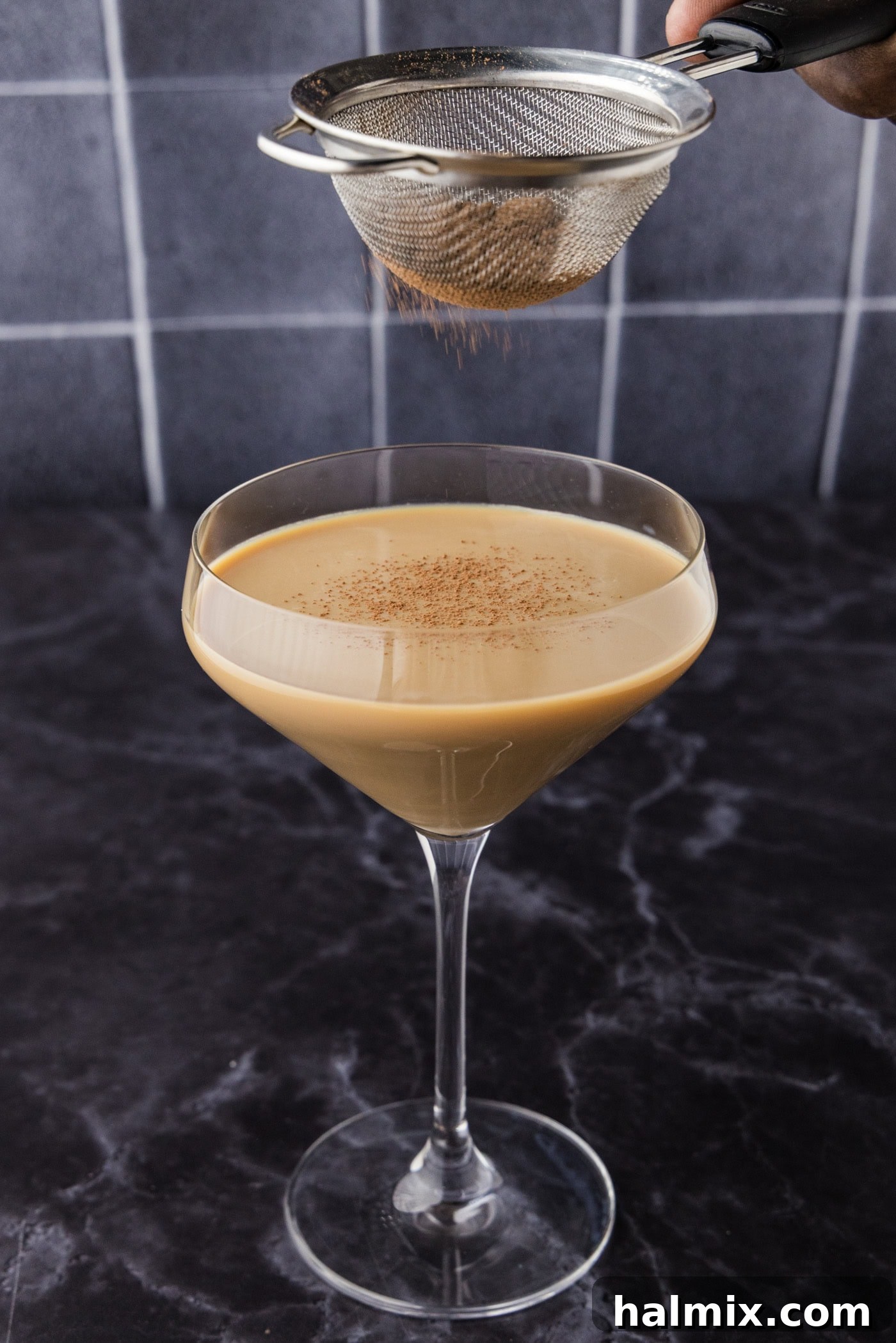 Dusting cocoa powder over Baileys chocolate martini with a small sieve
